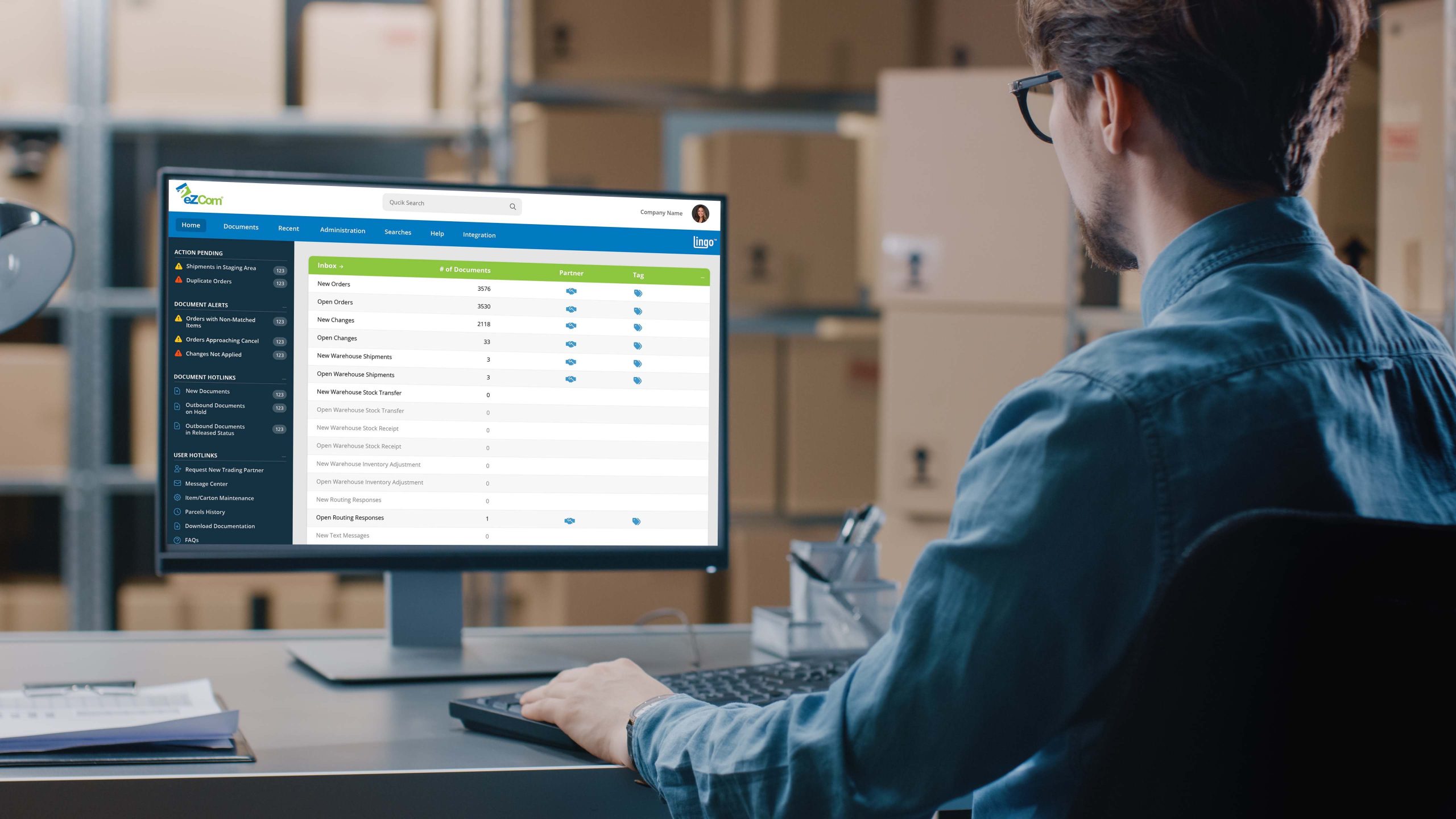 Person using eZCom Software's Lingo platform on a computer to manage EDI orders and document alerts in a warehouse setting.