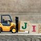 Small toy forklift pushing wood blocks with the letters J. I. T